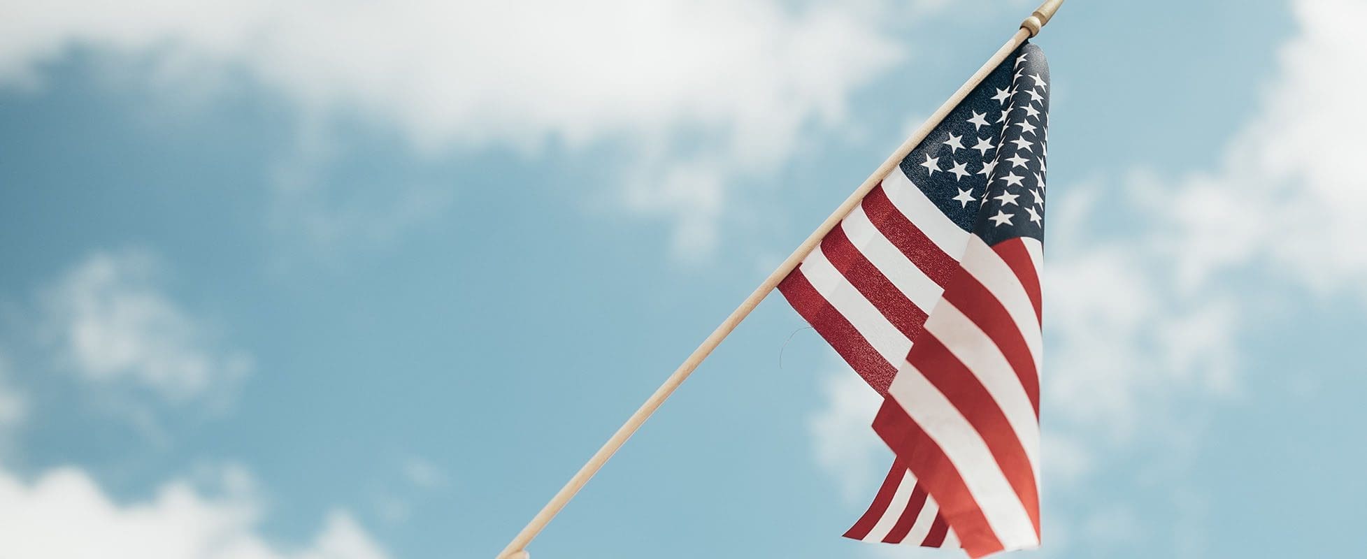 american flag waving in blue skies of summer