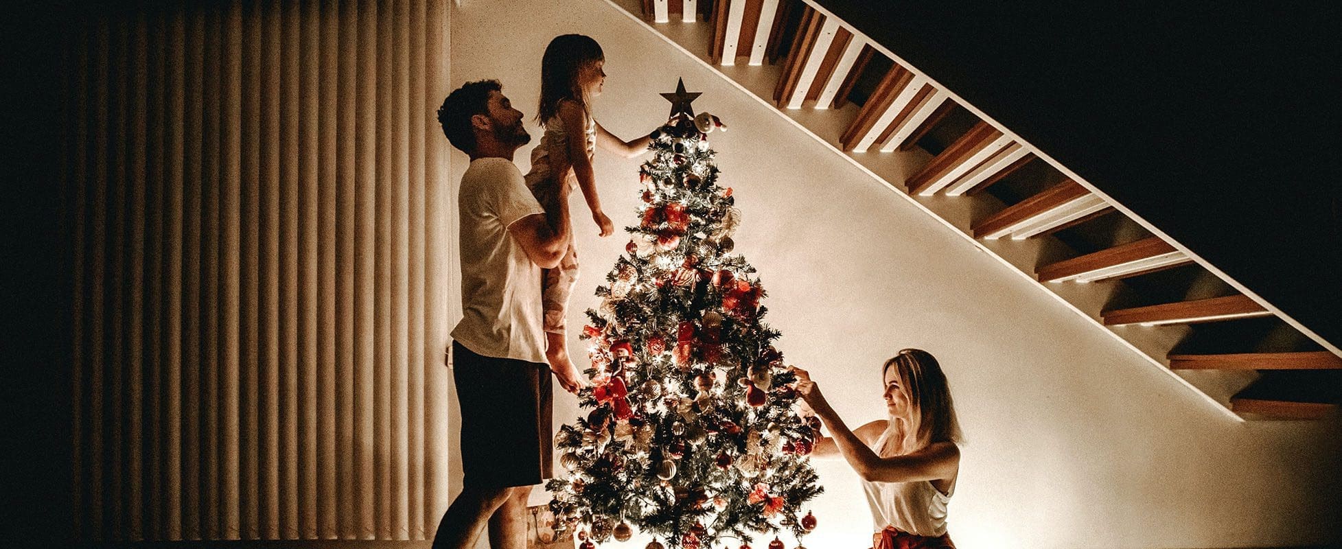 family decorating christmas tree at night