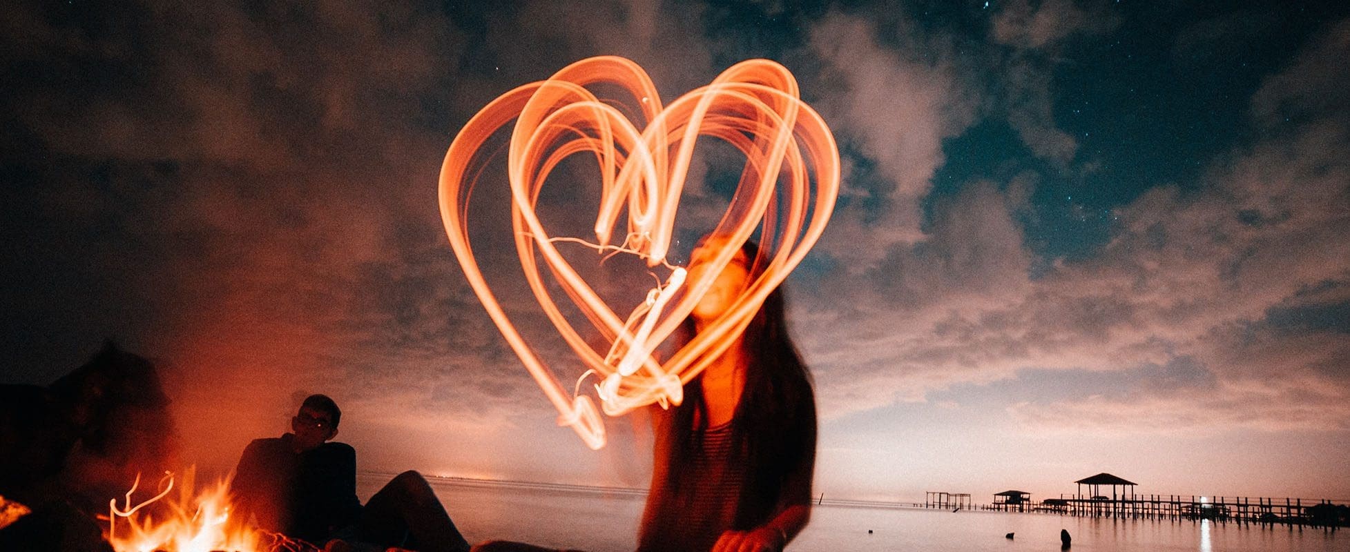 woman making heart out of light in the dark